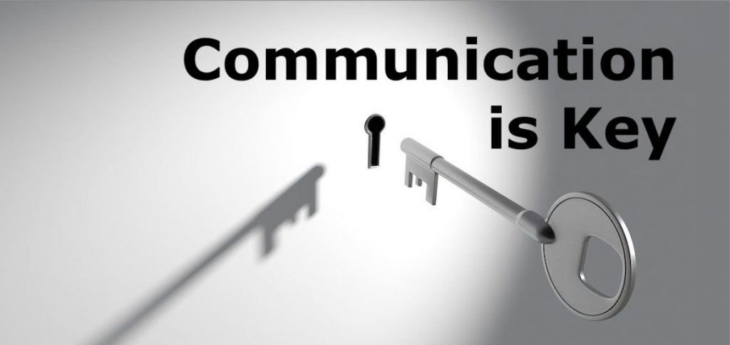 Une clé qui s'insère dans une serrure avec écrit "Communication is Key"
